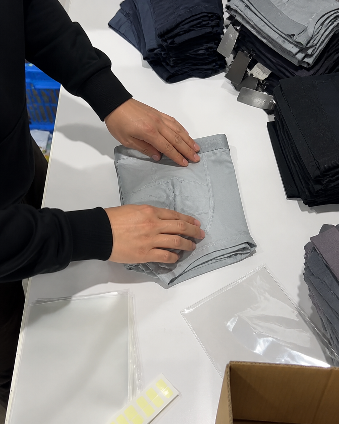 Packing staff performing final visual check on men's underwear before bagging or boxing